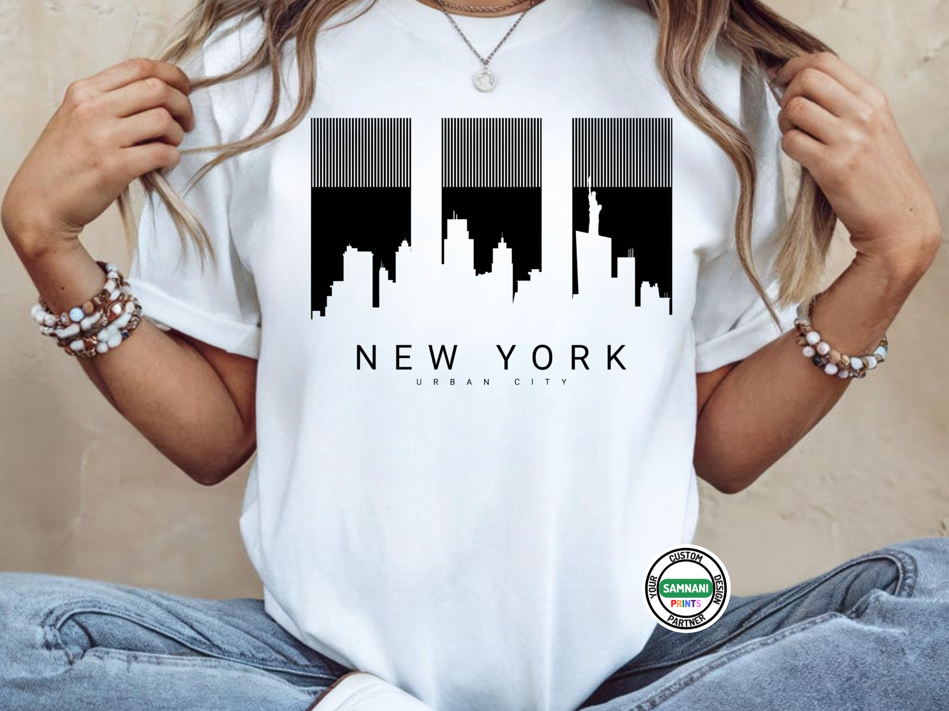 Person wearing a white t-shirt with a black and white cityscape design and 'New York' text.