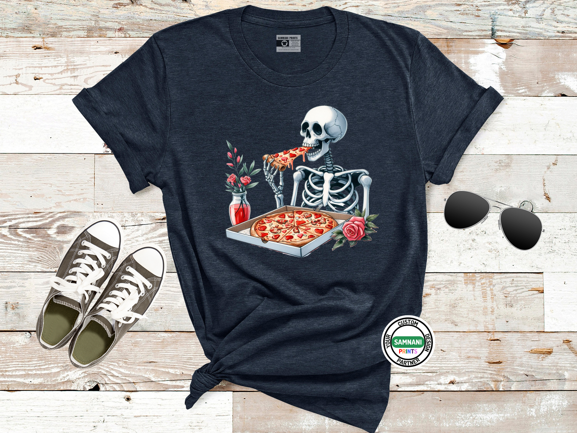 Navy blue graphic tee showing a humorous skeleton holding a pizza slice, paired with sunglasses and sneakers, ideal for Halloween lovers, foodies, and dark humor enthusiasts seeking bold designs.