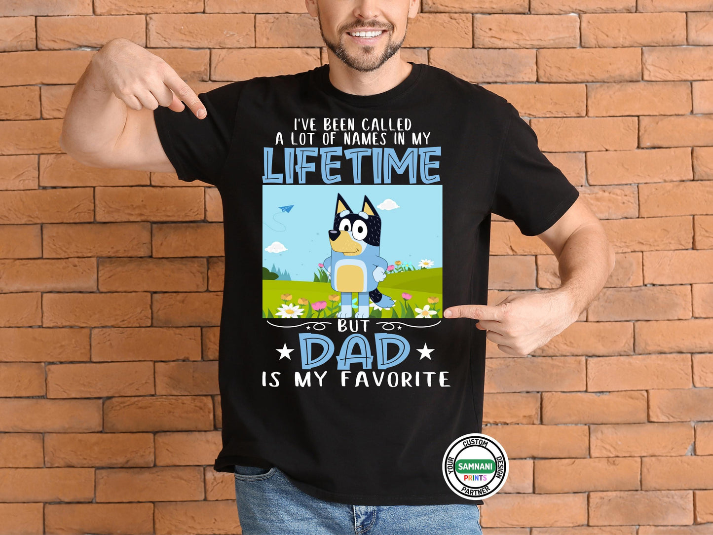 A man wearing a black t-shirt with a cartoon dad character in a field of flowers and text that reads “I’ve Been Called a Lot of Names in My Lifetime, But Dad Is My Favorite.”Bandit Bluey Dad Shirt – I've Been Called Many Names Tee – Gift for Funny Dads. Father's Day gift, gift for dad, gift for paw paw, gift for father. Bluey Bandit T-shirt and sweatshirt.