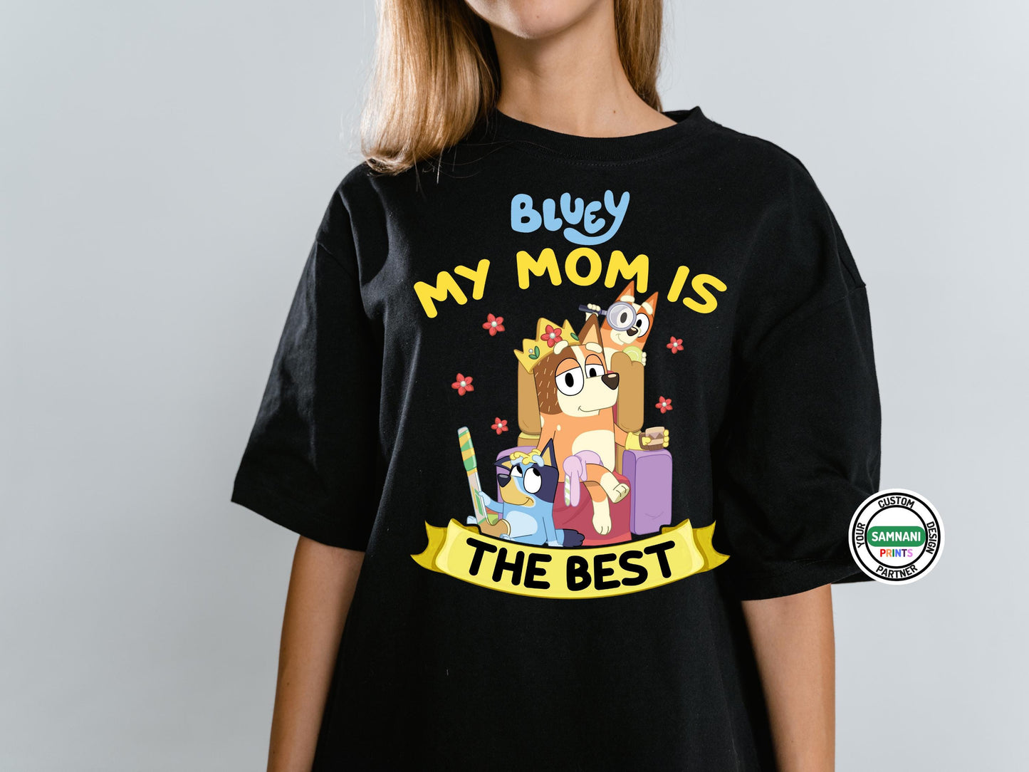 Bluey Cartoon Family Mom T-Shirt for Casual Wear – This Black Bluey t-shirt is designed for moms who love the show, featuring a cute Chilli, Bluey, and Bingo print with vibrant colors. Whether you&#39;re searching for a Mother&#39;s Day gift, a birthday surprise, or just a fun everyday shirt, this comfortable, high-quality t-shirt is perfect for any Bluey fan. Ideal for casual wear, this mom-themed Bluey shirt is a great way to show love for your favorite animated family.