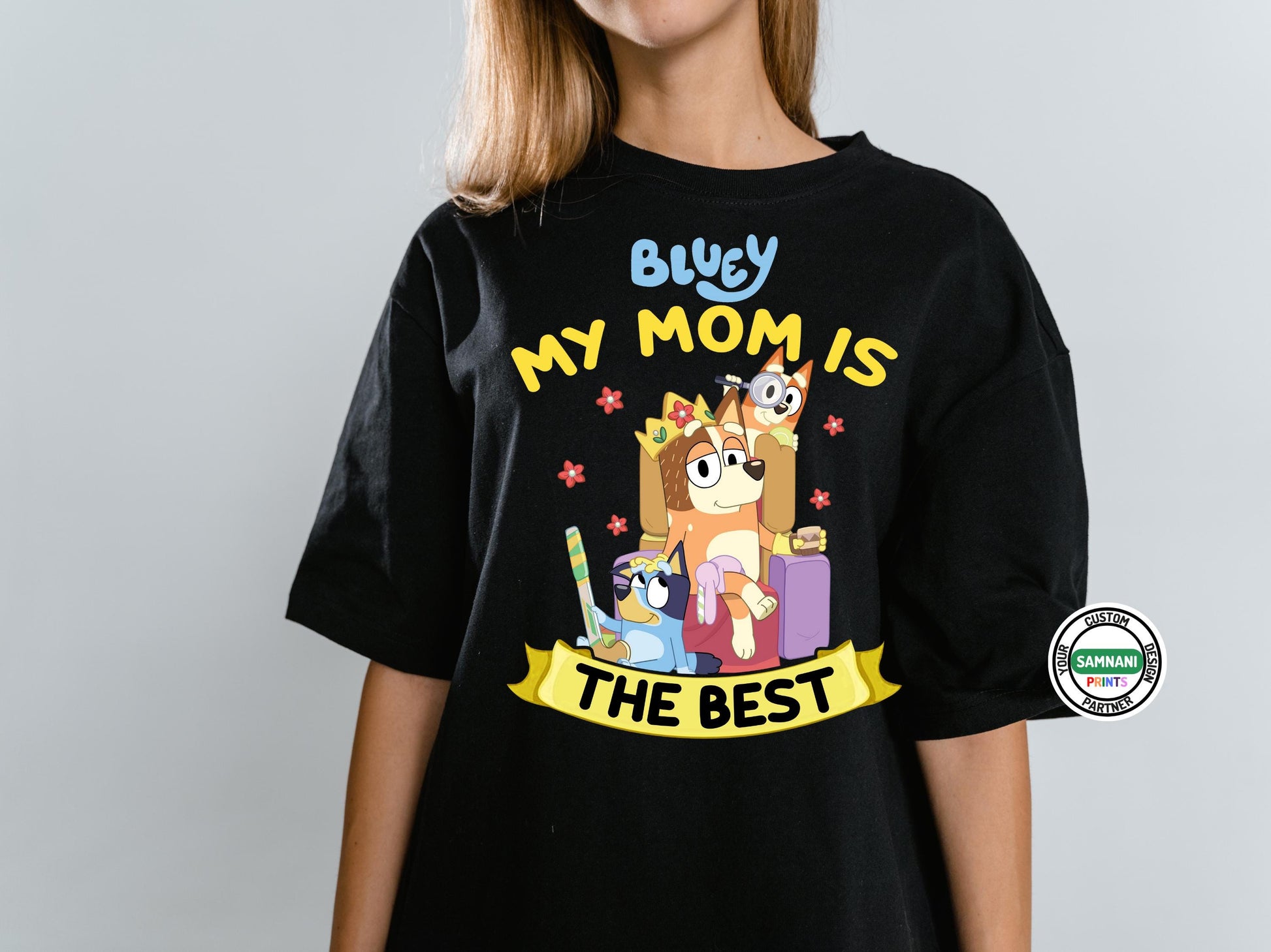 Bluey Cartoon Family Mom T-Shirt for Casual Wear – This Black Bluey t-shirt is designed for moms who love the show, featuring a cute Chilli, Bluey, and Bingo print with vibrant colors. Whether you&#39;re searching for a Mother&#39;s Day gift, a birthday surprise, or just a fun everyday shirt, this comfortable, high-quality t-shirt is perfect for any Bluey fan. Ideal for casual wear, this mom-themed Bluey shirt is a great way to show love for your favorite animated family.