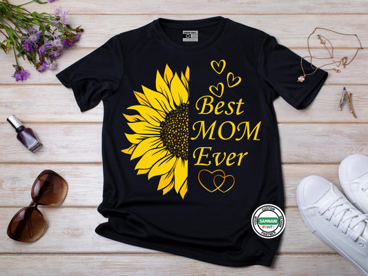 A flat lay Black t-shirt featuring a large yellow sunflower and &quot;Best Mom Ever&quot; text with heart accents, styled with sunglasses, flowers, and accessories. Mother&#39;s Day gift, gift for mom, gift for her, best mom ever gift, gift for mom under $20.