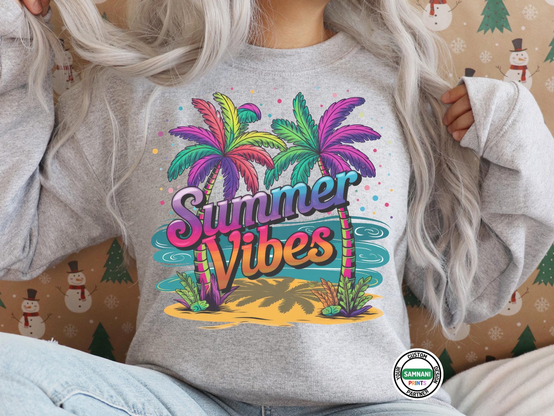 Women wearing a grey sweatshirt with a colorful “Summer Vibes” design featuring neon palm trees, waves, and a tropical island background sitting in front of a Christmas wallpaper background wearing denim jeans. Summer Vibes T-shirt, summer outfit, gift for her, bachelorette matching shirts, birthday gift, gift for birthday, cruise t-shirt, family cruise matching t-shirts, matching family t-shirts, gift for him, gift for mom, mother&#39;s day gift, gift for mother.